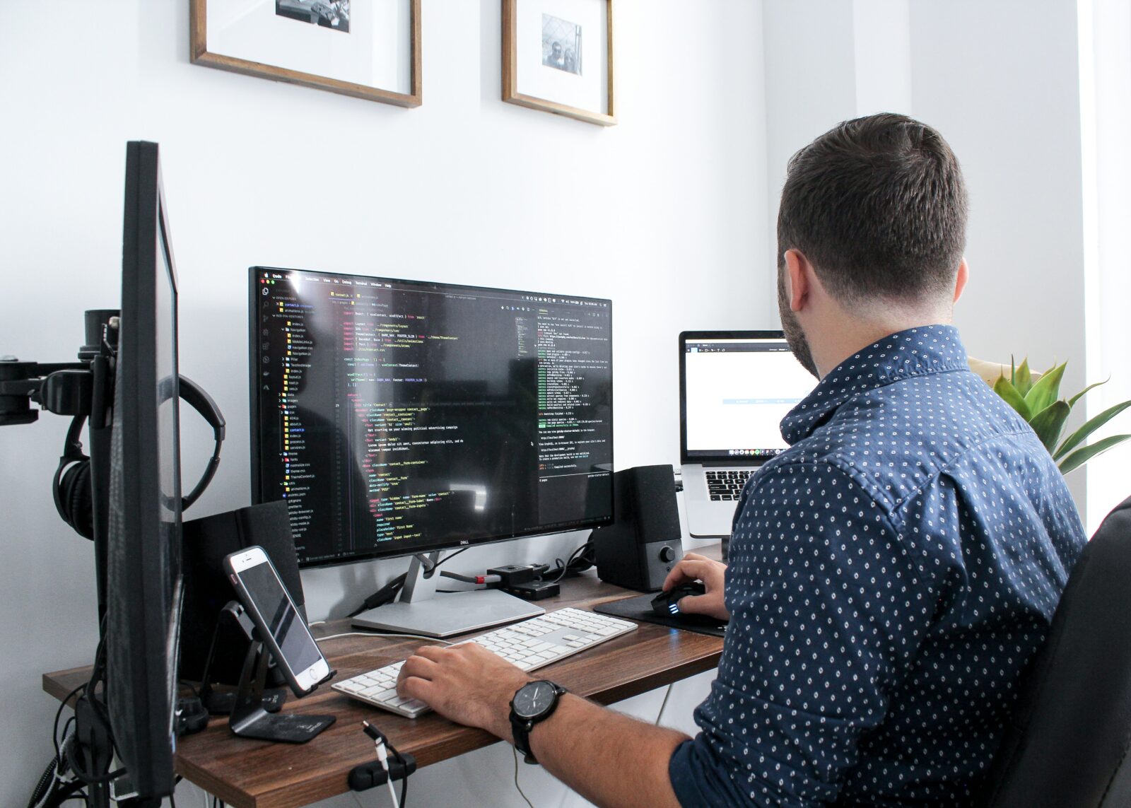 Someone sitting at a desk, working with three screens